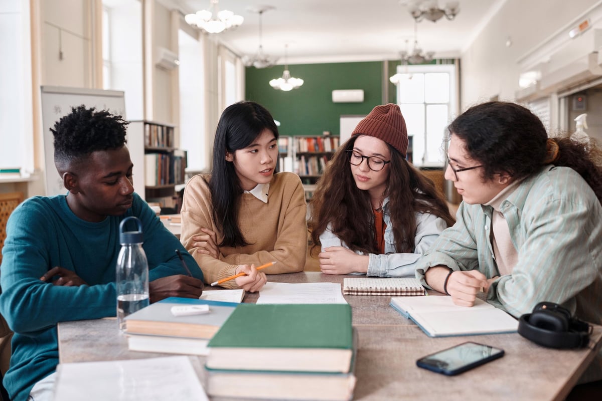 Multiethnic group of students discussing a project in a library